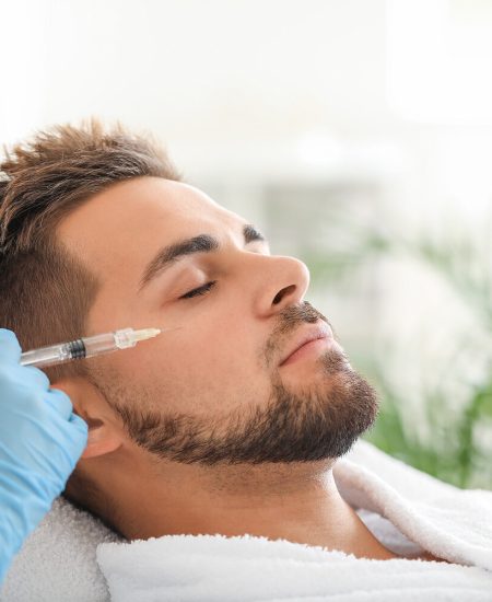 Handsome man receiving filler injection in beauty salon